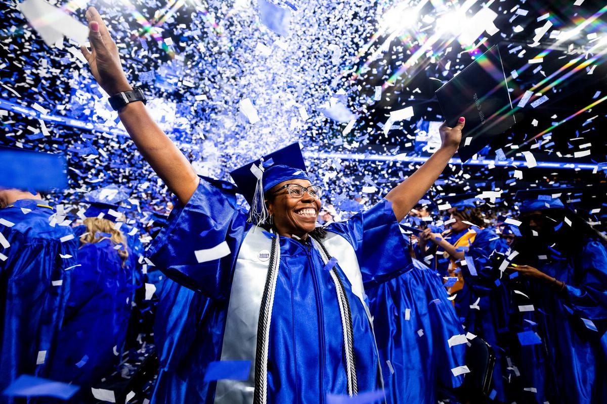 student in graduation robe as confetti is in the air